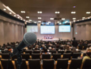 Microphone over the Abstract blurred photo of conference hall or