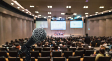 Microphone over the Abstract blurred photo of conference hall or