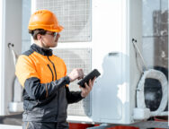 Workman servicing air conditioning or heat pump with digital tablet
