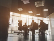 Silhouettes of people sitting at the table. A team of young businessmen working and communicating together in an office. Corporate businessteam and manager in a meeting