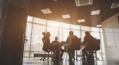 Silhouettes of people sitting at the table. A team of young businessmen working and communicating together in an office. Corporate businessteam and manager in a meeting