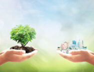 Sustainable development goals (SDGs) concept: Two human hands holding tree and city over blurred nature background