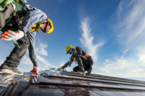 Two male workers wearing safety clothes Installing the roof tile