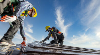 Two male workers wearing safety clothes Installing the roof tile