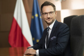 Minister_rozwoju_i_technologii_Waldemar_Buda,_poziom,_w_tle_flagi_PL_i_UE