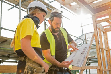 male and female construction workers discuss the building plans inside the building site