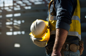 Construction worker holding his helmet while looking at construc