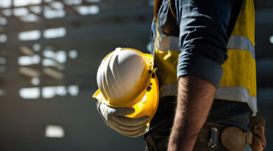 Construction worker holding his helmet while looking at construc