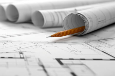 Na stole widzimy rozwinięte rolki architektoniczne z precyzyjni